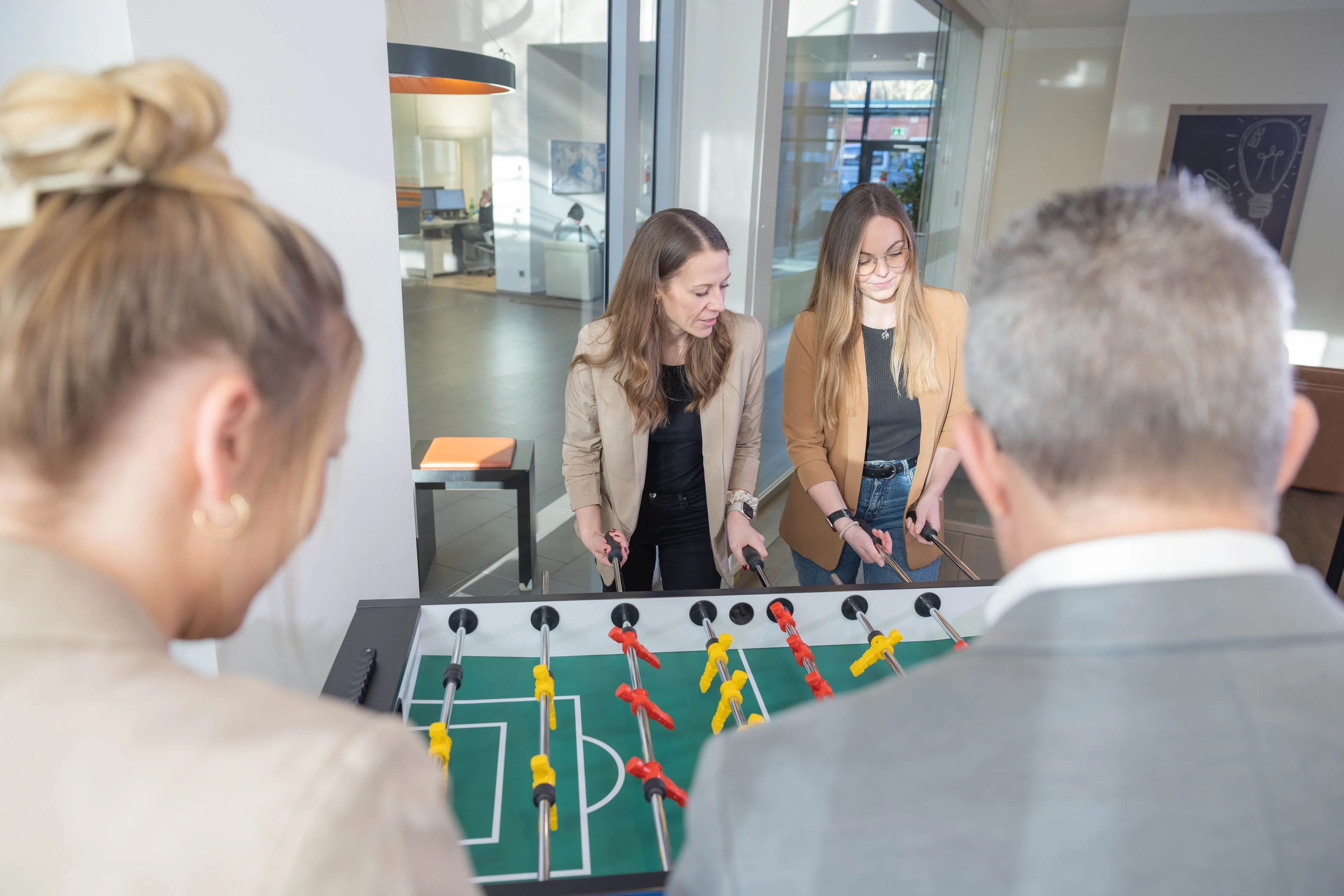 4 Mitarbeiter spielen Kicker